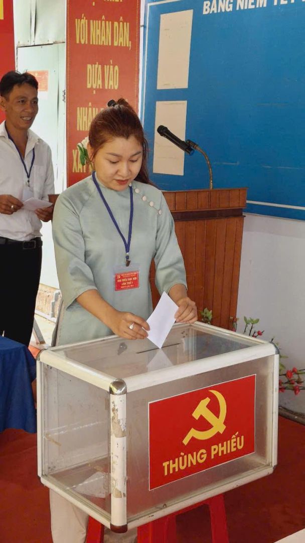 A person putting a piece of paper in a ballot boxDescription automatically generated