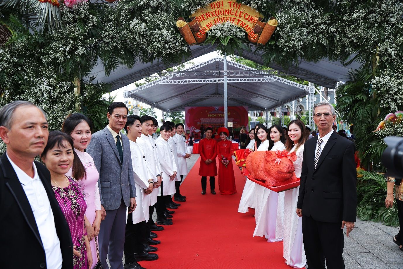 A group of people standing on a red carpetDescription automatically generated