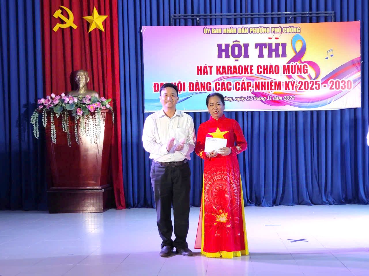 A person and person standing in front of a stage with a signDescription automatically generated