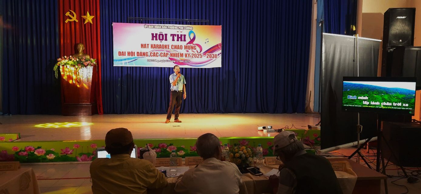 A person on a stage with a bannerDescription automatically generated