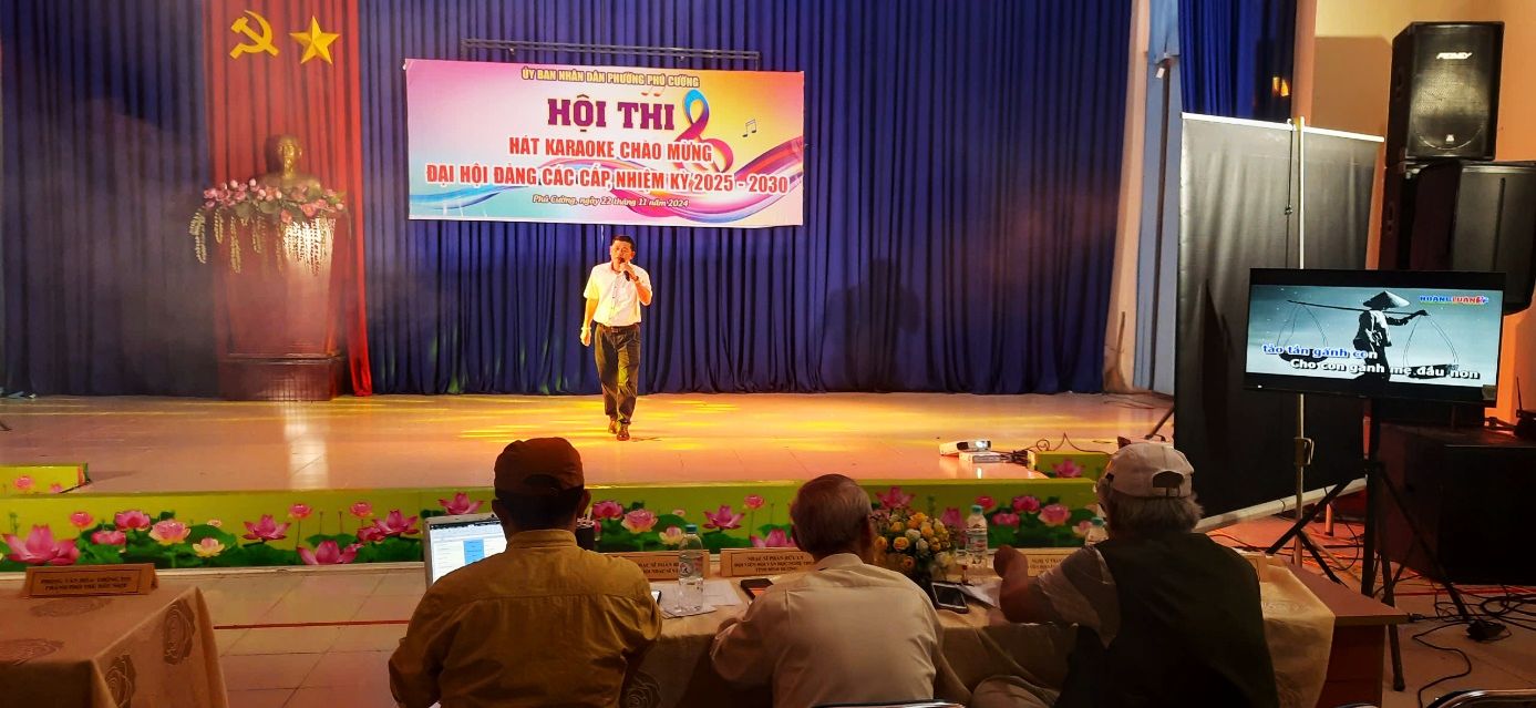 A person on a stage with a bannerDescription automatically generated