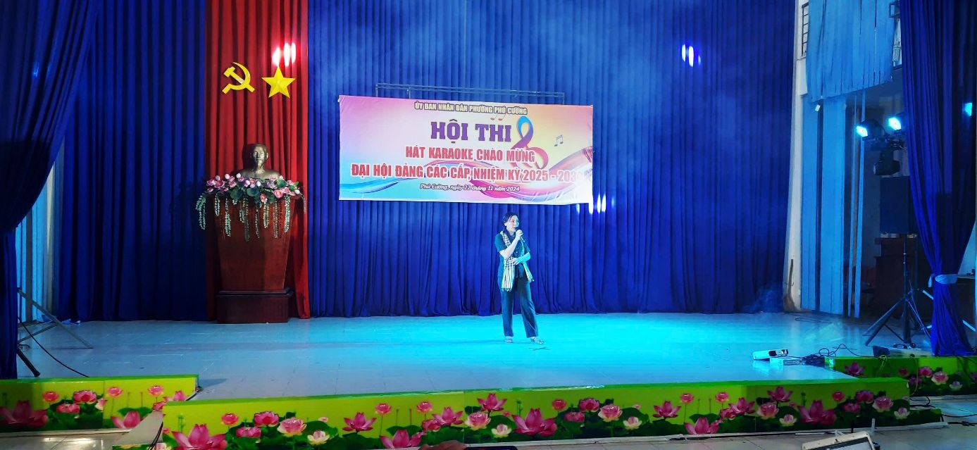 A person on a stage with a bannerDescription automatically generated