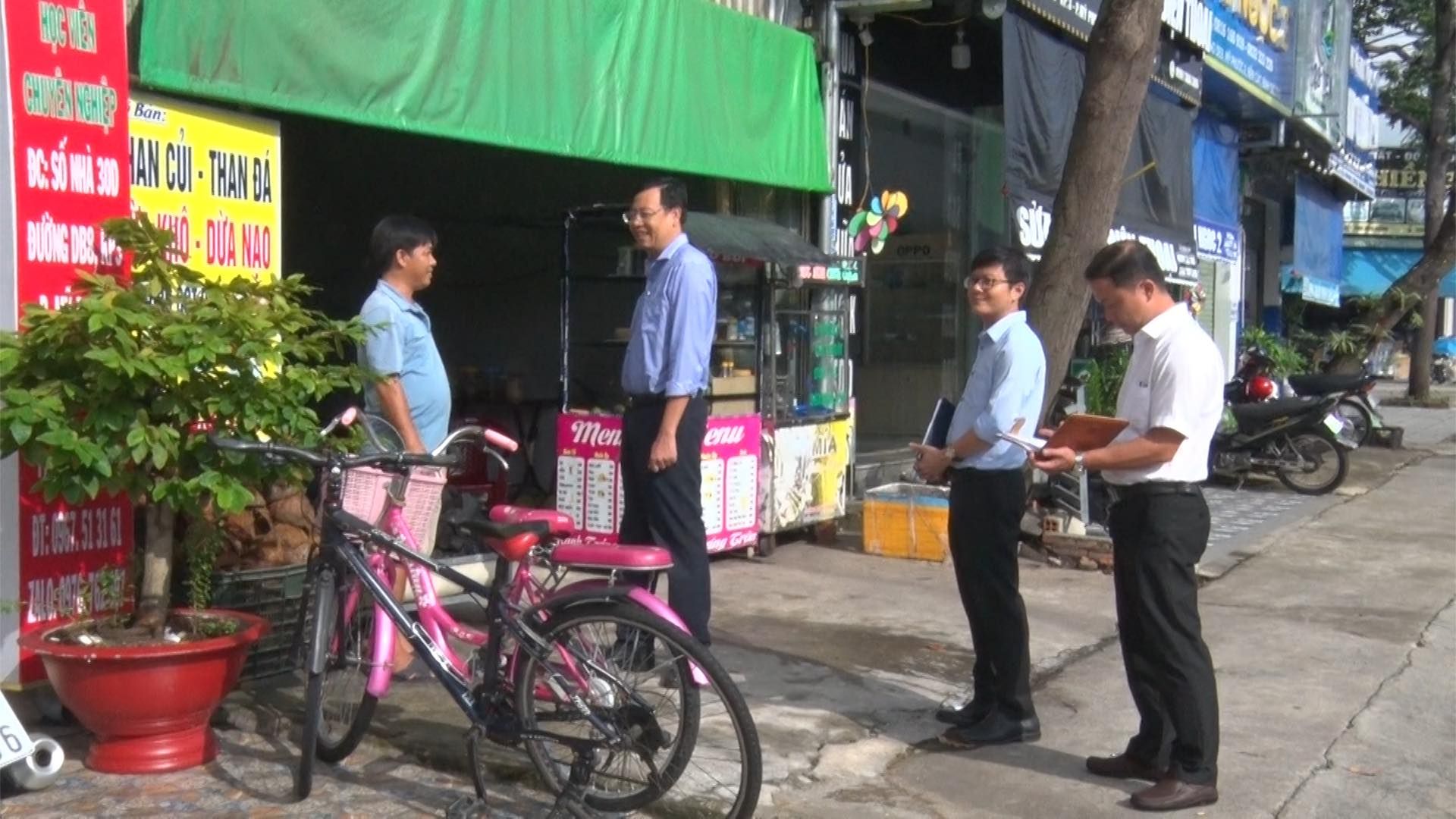 Có thể là hình ảnh về 4 người, máy thu tiền đỗ xe, xe đạp, quầy báo, đường phố và văn bản