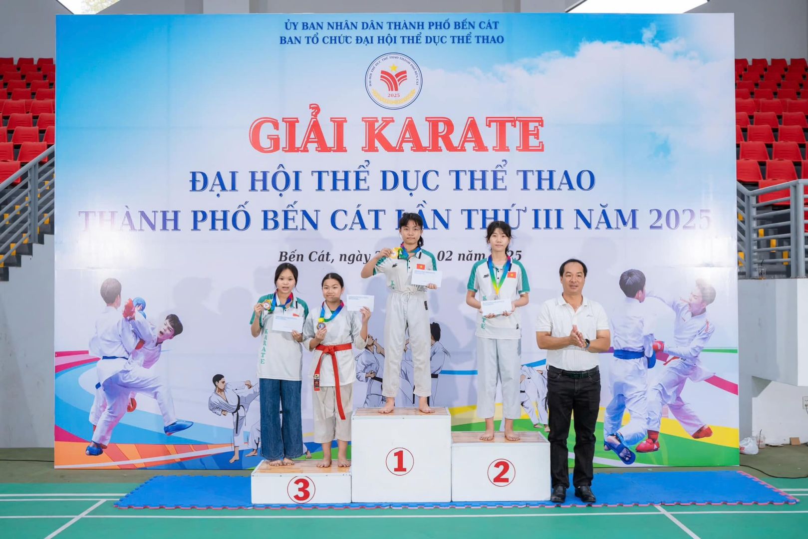 Có thể là hình ảnh về 9 người, đang trình diễn võ thuật và văn bản cho biết 'ỦY BAN NHĂN DAN THÀNH PHỐ BÉN CÁT BAN TỔ CHỨC ĐẠI HỘI THÊ DỤC THE ΓHAΟ GIẢI KARATE ĐẠI HỘI THỂ DỤC THỂ THAO THO THÀNH PHỐ BẾN CÁT ININ THỨ III NĂM 2025 Bến Cát, ngày 02 năm 1 3 2'