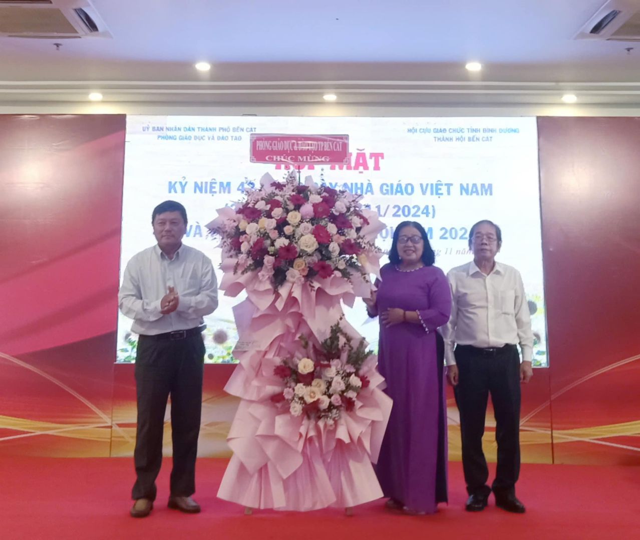 Có thể là hình ảnh về 3 người, hoa, cái bục và văn bản