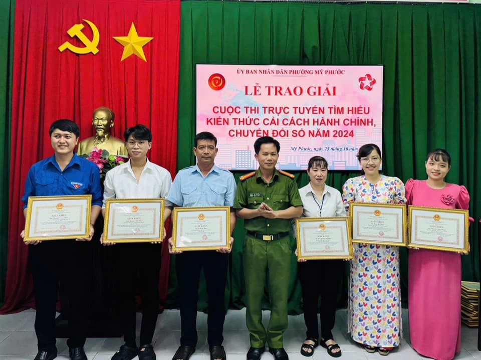 Có thể là hình ảnh về 7 người và văn bản cho biết '人 ا۱ BAN NHÂN ĐÂN PHƯỜNG MỸ PHƯỚC LE TRAO GIẢI CUOC THI TRỰC y ι HIEU KIEN t CẢI CÁCH HÀNH CHÍNH, CHUYEN ĐOI So NĂM 2024 Mj Phanic በ 25 nhn กฟัง พลิม e'